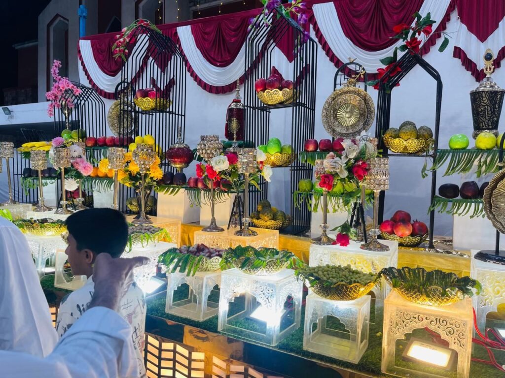 : Decorated outdoor wedding catering buffet counter with floral arrangements iron cage decor and warm lighting at night